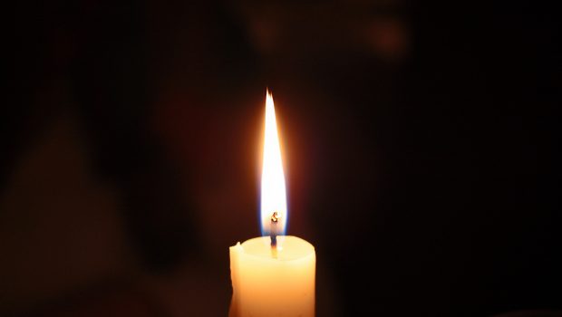 A lighted candle burning in the dark.