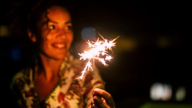 A smiling, middle-age woman holding a sparkler