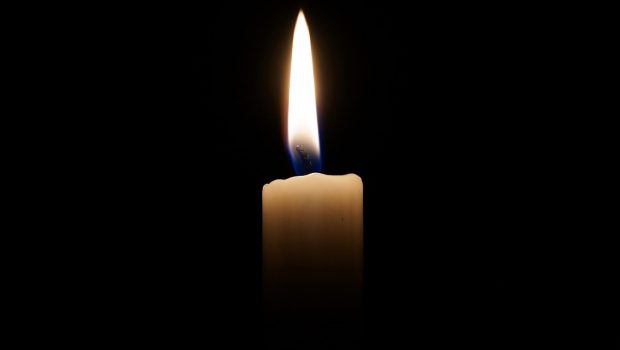 A single candlelight lit against a pitch black background.