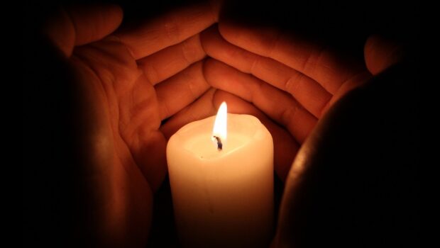 Candlelight being protected by a pair of hands
