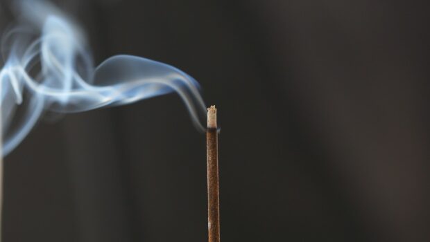 A lighted incense stick against a black background